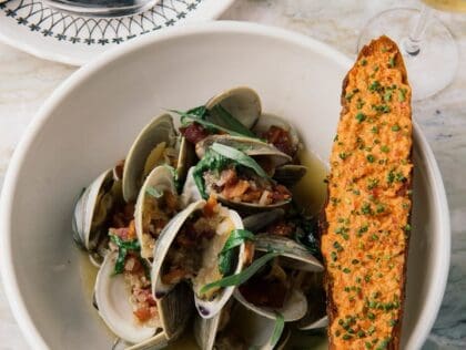 White bowl filled with clams and a side of seasoned bread at Seaworthy restaurant in New Orleans