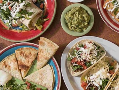 Plated tacos with sauce and garnish on a black tray at Tacos Del Cartel in Nola